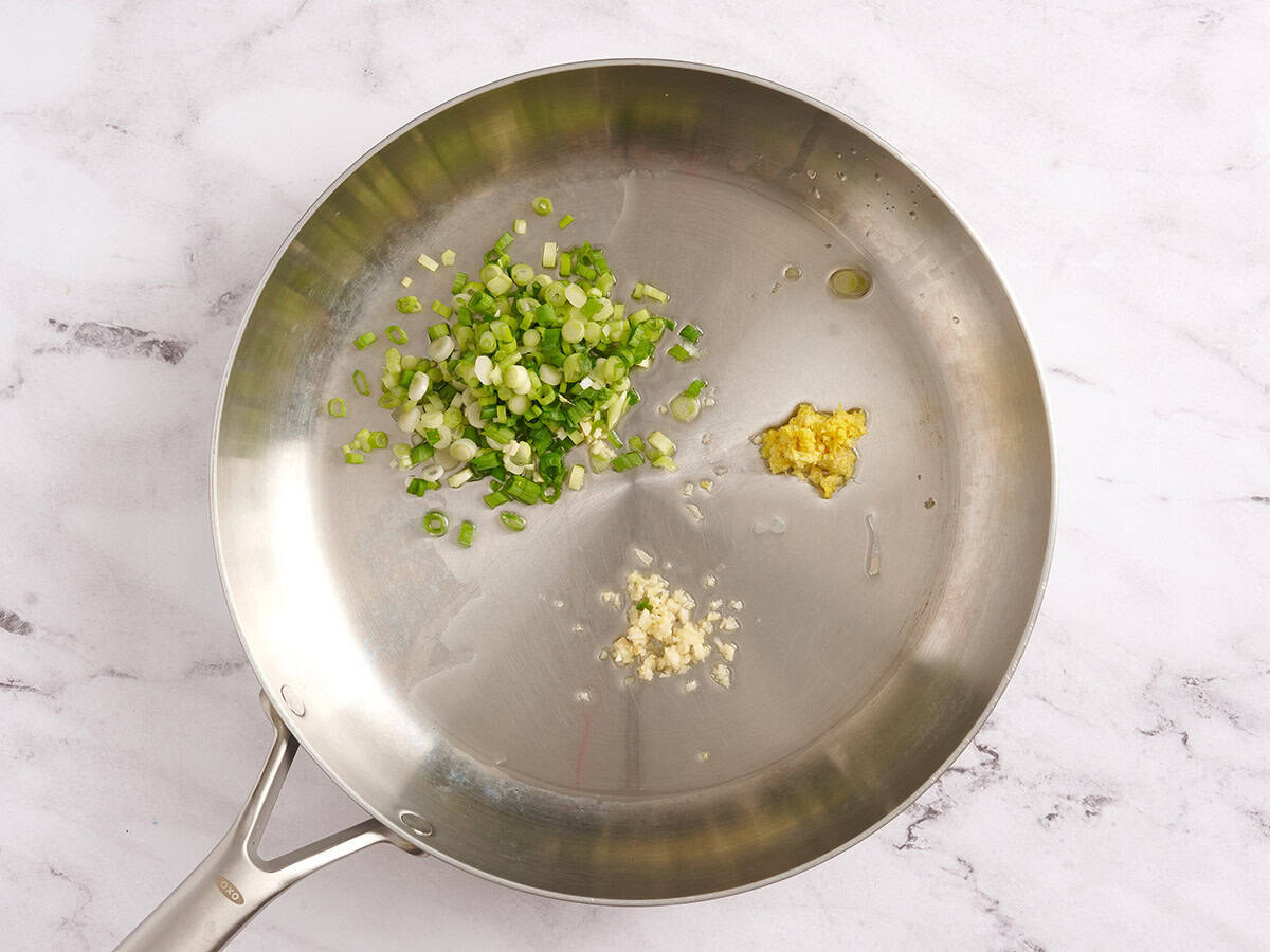 Diced green onion, minced garlic and ginger in a skillet.