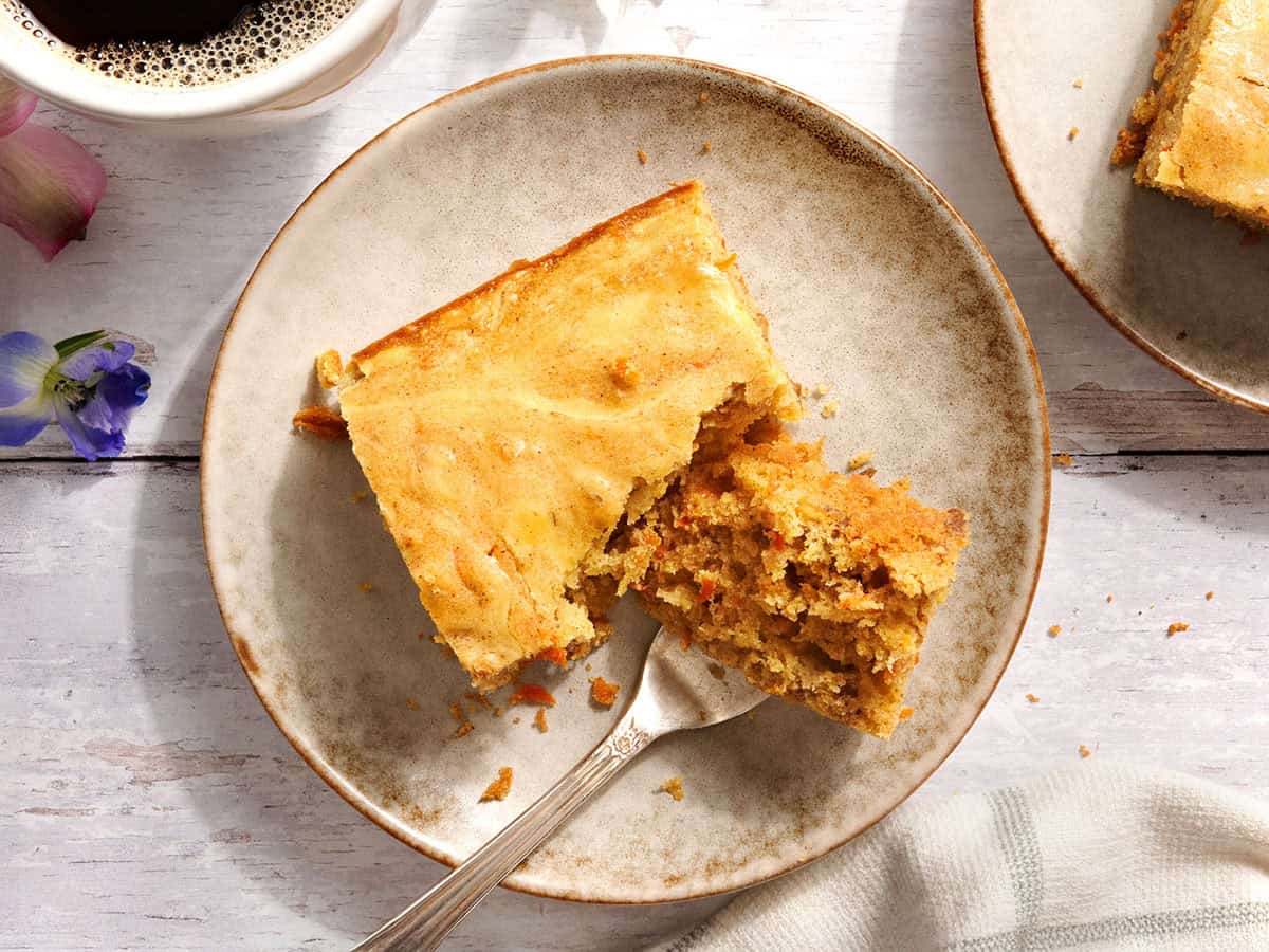 Overhead view of a carrot cake bar on a plate with a fork.