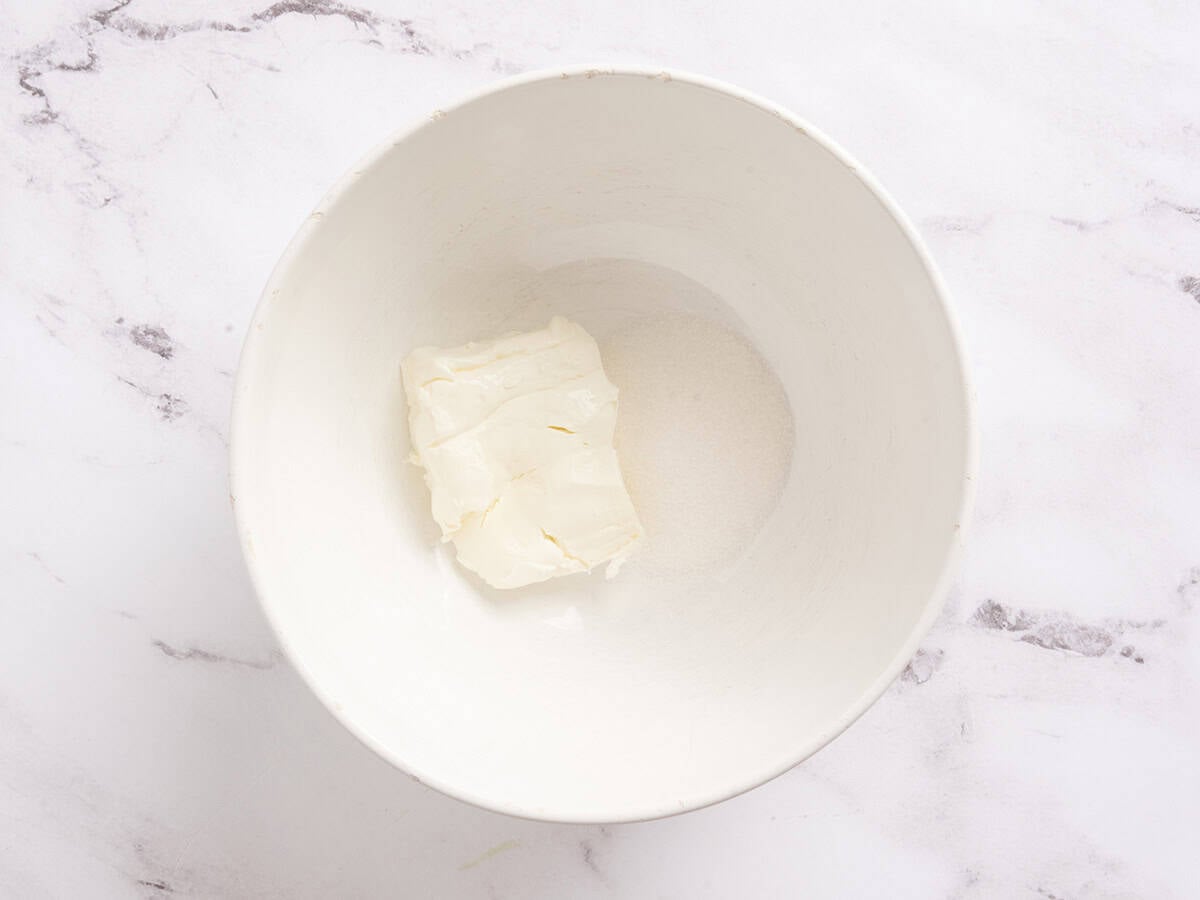 Sugar and cream cheese added to a mixing bowl.