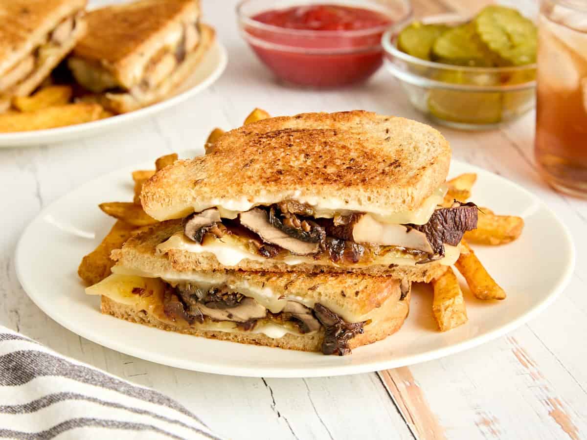 Side view of a mushroom patty melt and fries on a plate.