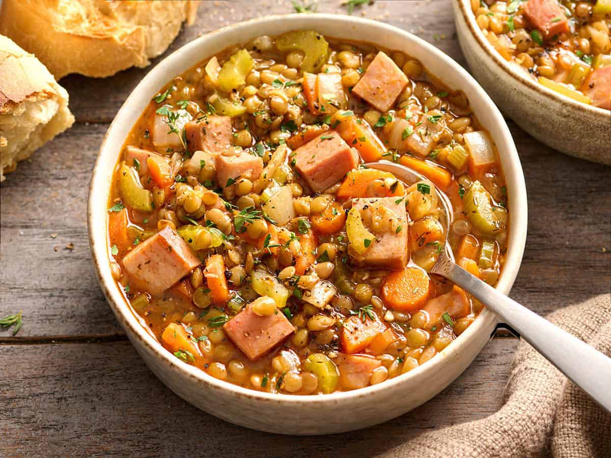 Overhead side view of a bowl of ham and lentil soup.