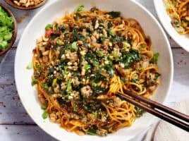 Overhead view of a bowl of dan dan noodles with chopsticks.