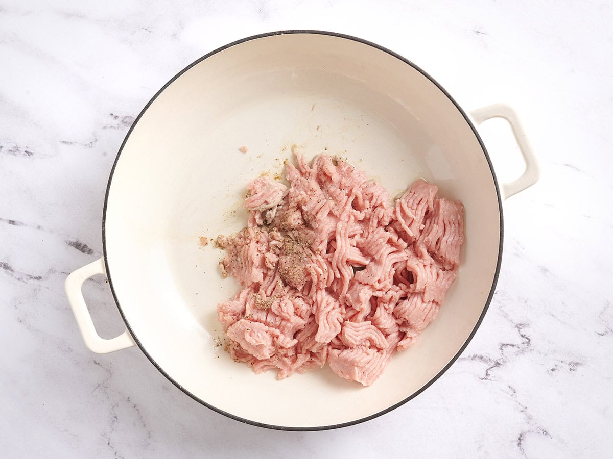Ground turkey seasoned with salt and pepper in a skillet. 