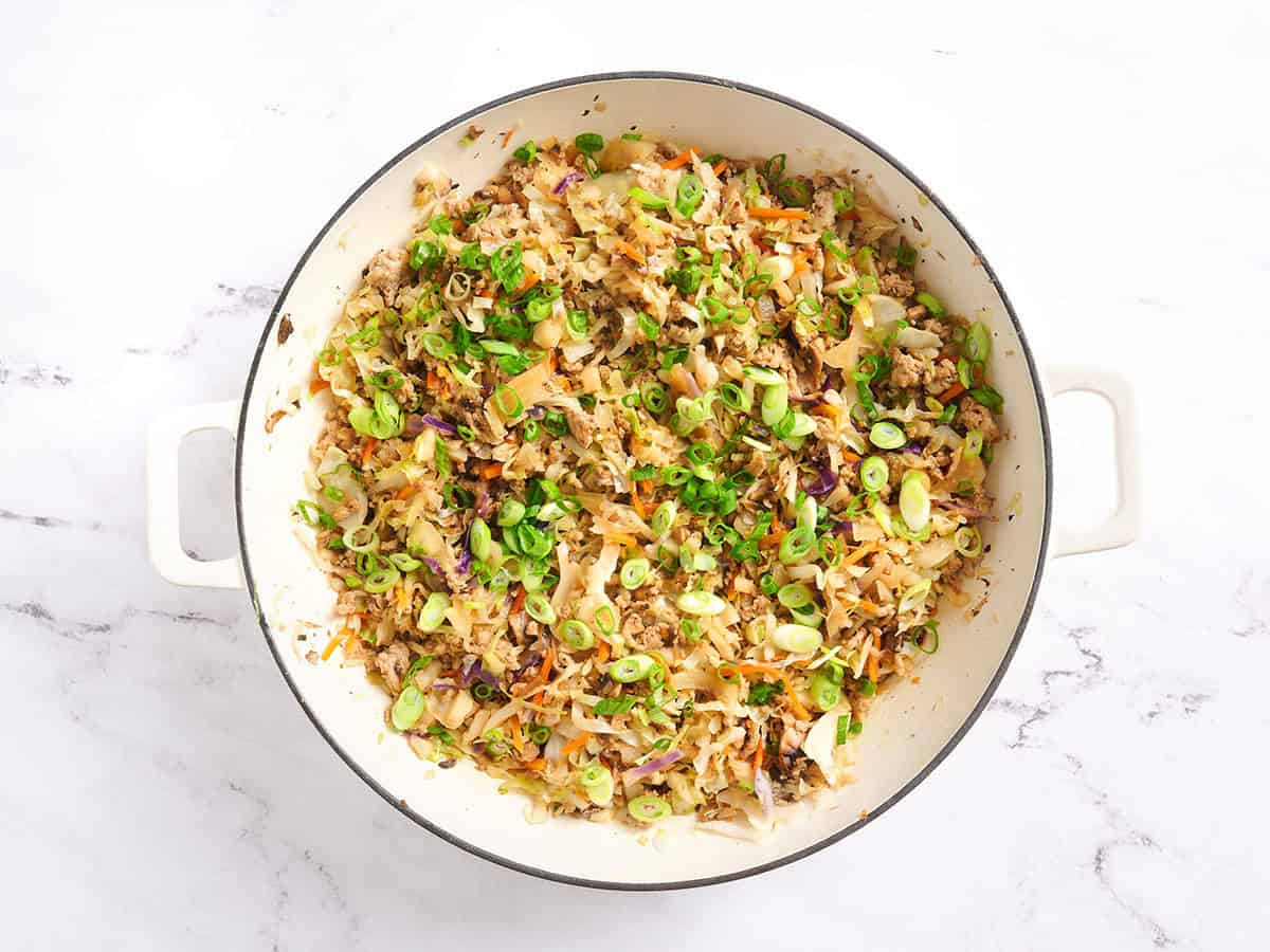 Eggroll in a bowl garnished with green onions and sesame seeds. 