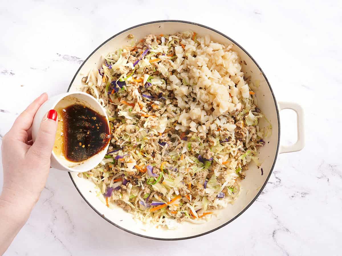 Adding the sauce and water chestnuts to the skillet with the turkey and vegetables. 