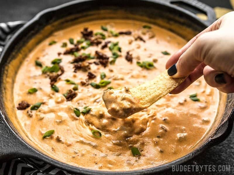 A chip scooping up Spicy Chorizo Cheese Dip
