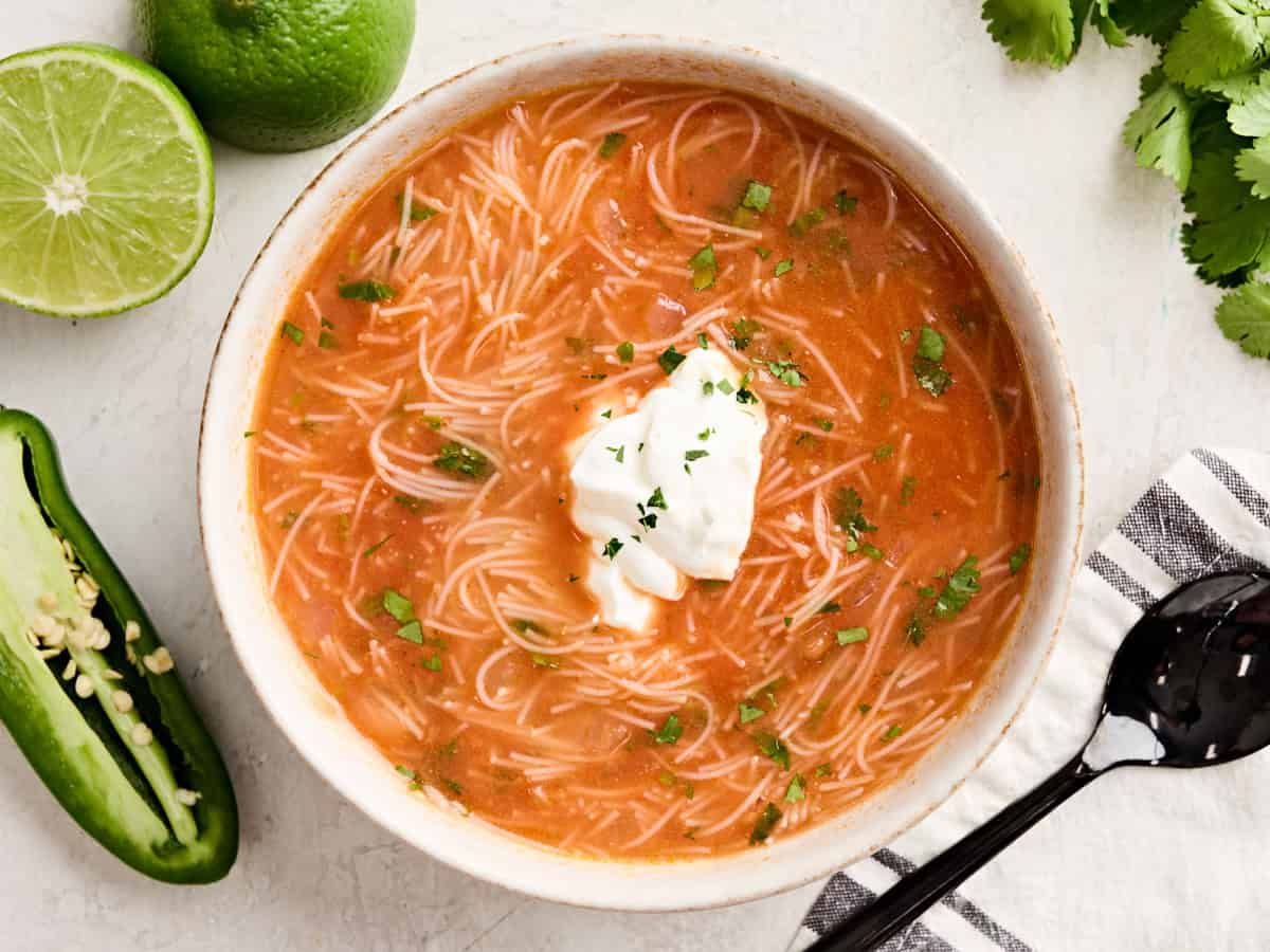 Overhead view of homemade sopa de fideo in a bowl topped with sour cream.