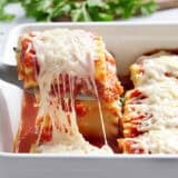 lasagna roll up pulled out of casserole dish on a spatula