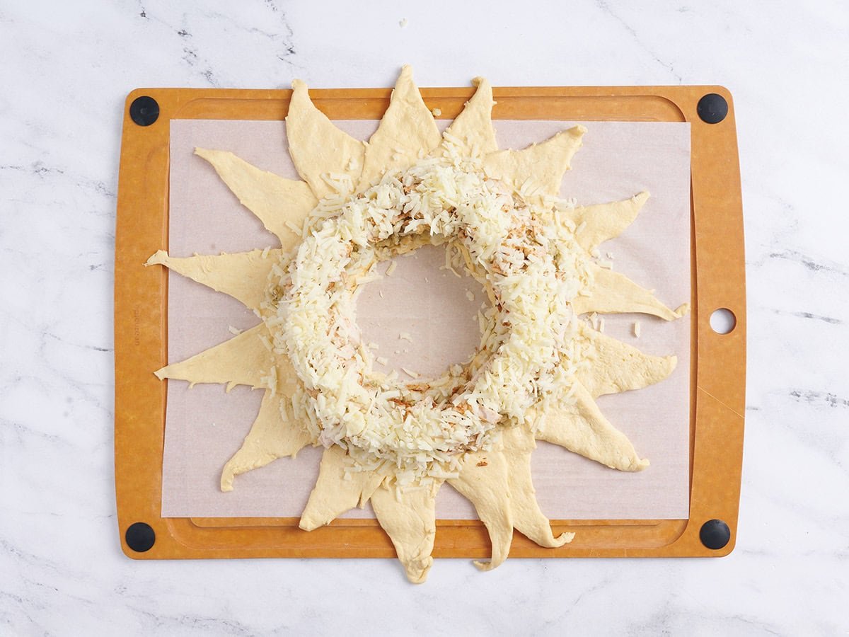 Adding cheese to the wreath.
