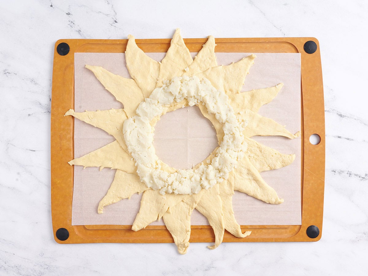 Placing the mashed potatoes inside the rolled out crescent rolls. 