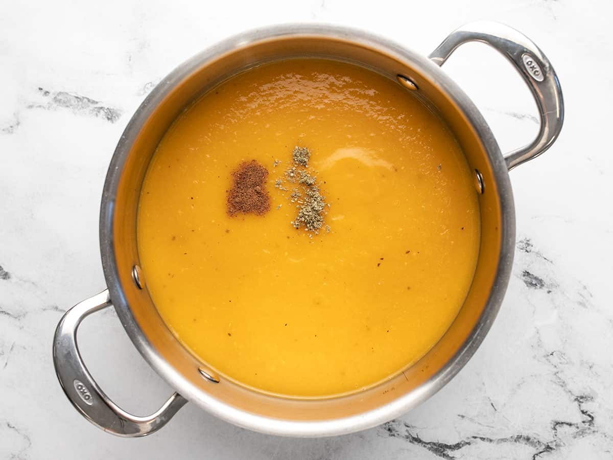 Butternut squash soup in a pot with herbs added.