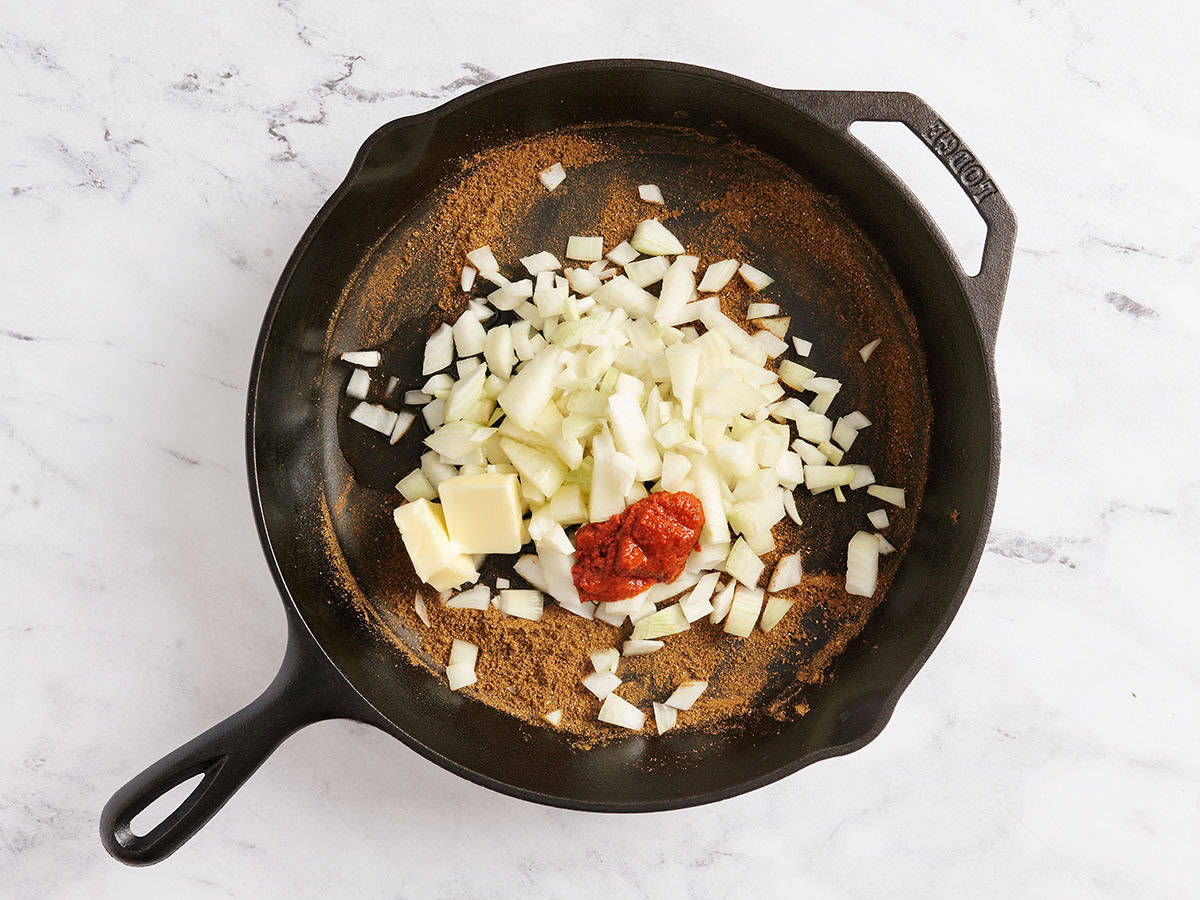 Diced onion in a skillet with red curry paste.