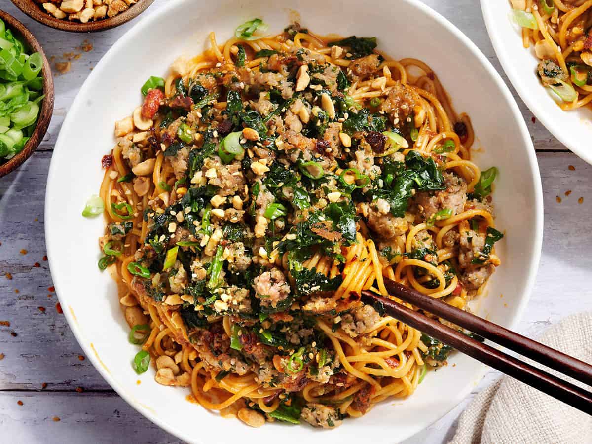 Overhead view of a bowl of dan dan noodles with chopsticks.