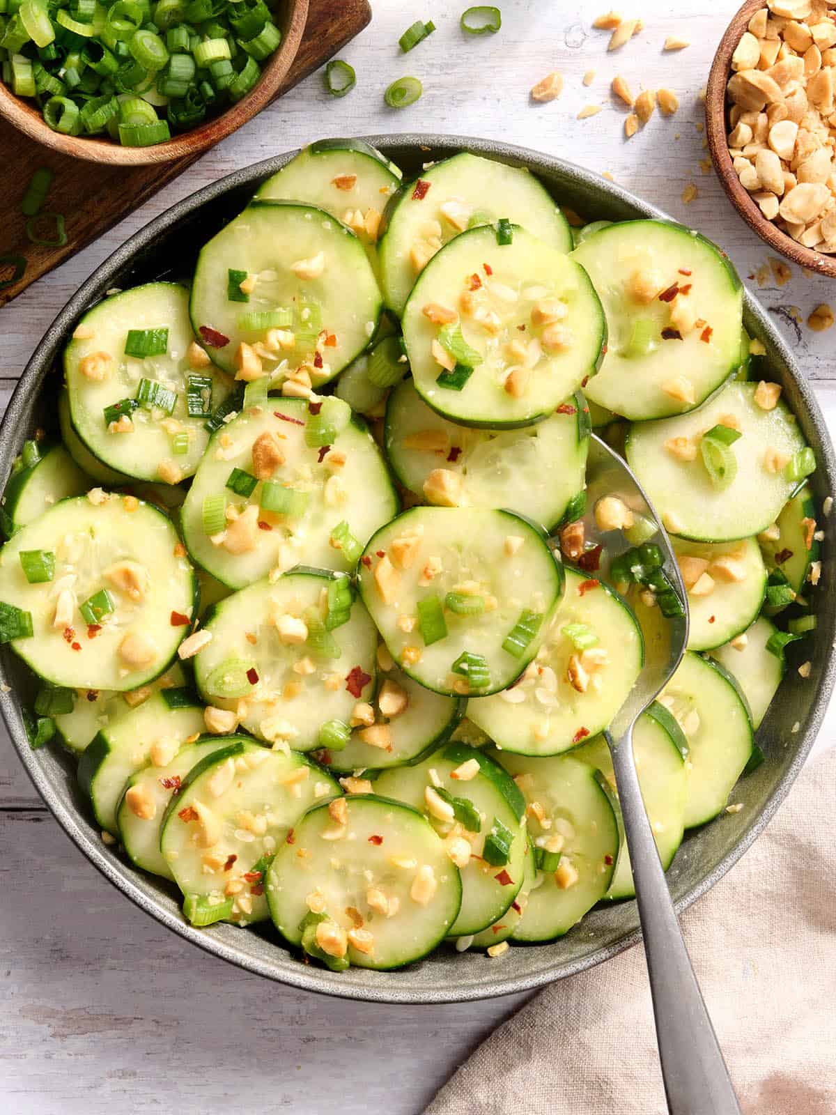 Overhead view of a bowl of sesame cucumber salad with a spoon.